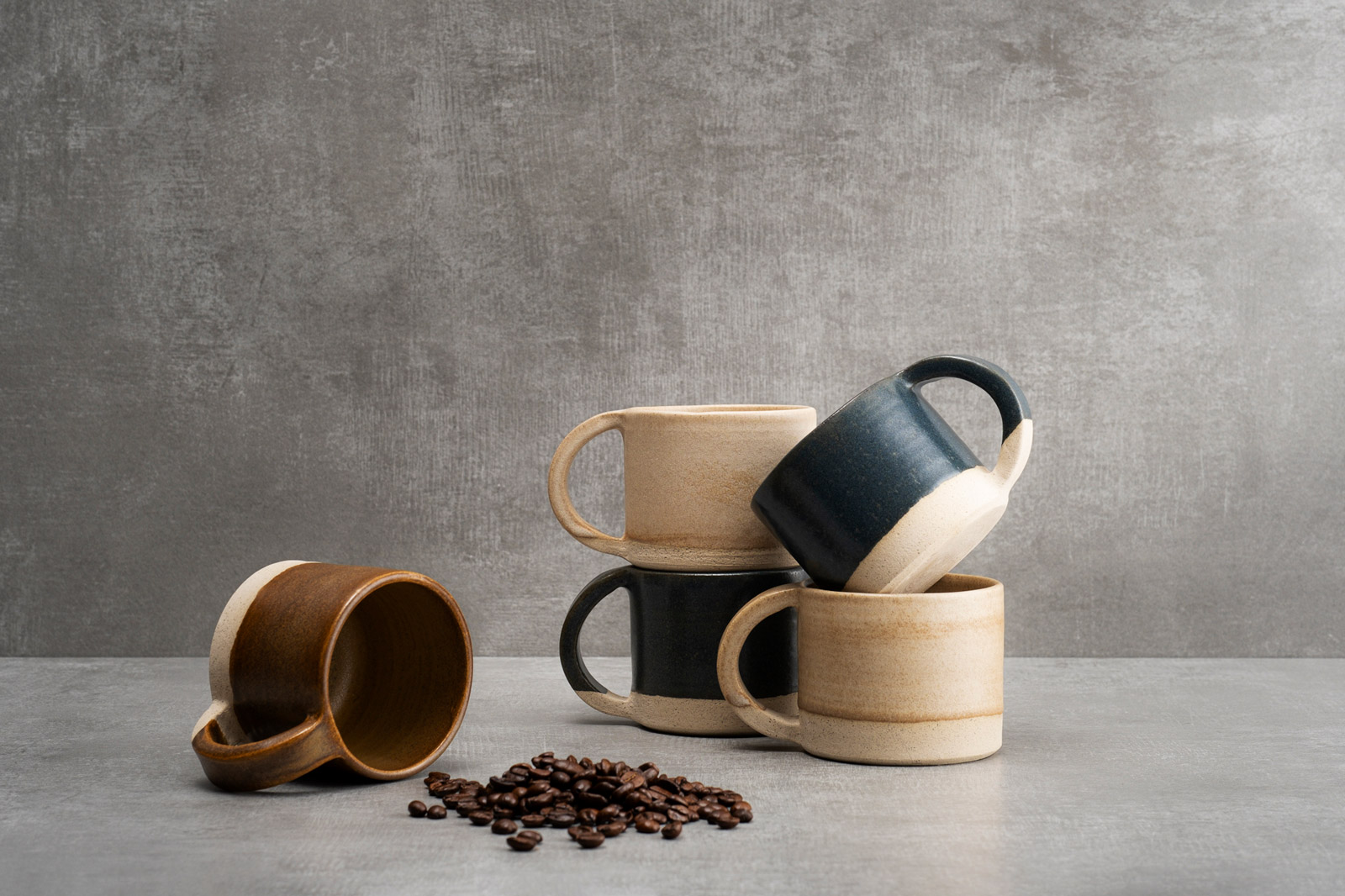 Composizione di tazze in ceramica e chicchi di caffè su fondo grigio