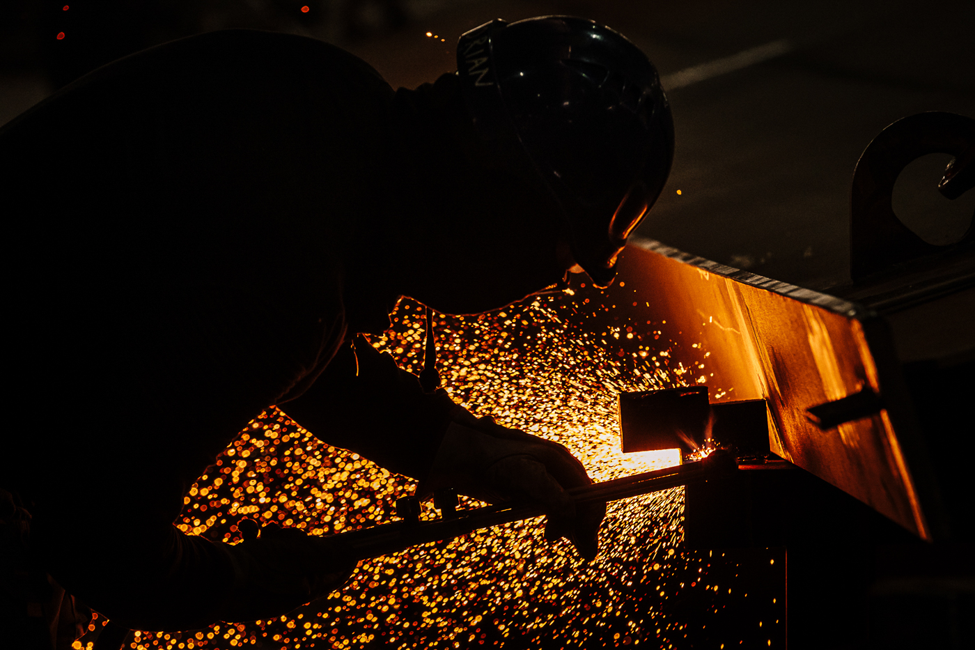Operaio al lavoro tra scintille e luce arancione in ambiente industriale